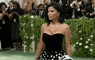 Met Gala 2024 gif. Lauren Sanchez poses for the cameras wearing a strapless black dress with mosaic detail skirt.