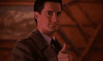 TV gif. Kyle MacLachlan as Dale Cooper on Twin Peaks gives a straight-faced thumbs up, as lightning lights up the room.