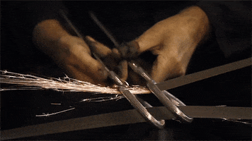 Video gif. A pair of hands scrapes two metal rings against two thin strips of metal, creating sparks.
