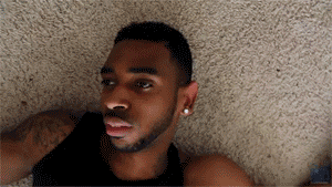 Video gif. A man lies deadpan on the floor. The view spins as it moves farther away from him.