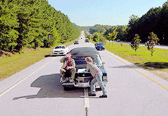 Movie gif. Jim Carrey as Lloyd Christmas and Jeff Daniels as Harry Dunne have parked their car in the middle of the highway, on the centerline. Lloyd sits on the hood of the car, drinking a coffee, while Harry leans nonchalantly on the hood of the car, looking at a map.