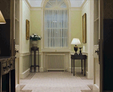 Movie gif. In a scene from Love Actually, we see an empty residential hallway, then Hugh Grant as The Prime Minister shimmies gleefully from one doorway to another.