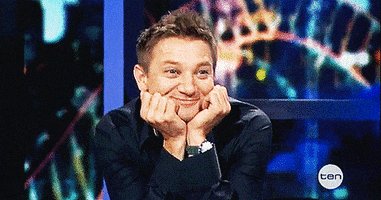Celebrity gif. Jeremy Renner has his arms up on a table and his head resting in both his hands. He lovingly stares with a big smile on his face, swooning. 