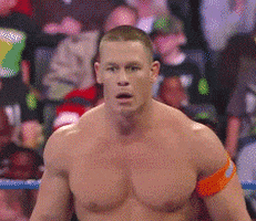 Sports gif. John Cena from WWE heaves big breaths as he stops and stares at something, stunned.