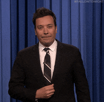 Tonight Show gif. Jimmy Fallon in front of his blue curtain, stretches his hand out to hold us off, pulling a quick dance move to dip out of frame.