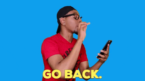 a man is blowing a kiss while looking at his cell phone .