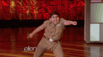 Video gif. Young boy on the Ellen Show dances in a circle, shaking his hips and throwing his arm in the air.