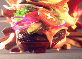 Video gif. A cheeseburger with lettuce, tomato, onions, spread, and fries falls, all of the toppings spreading slightly, before the burger lands and everything bounces and fits back together satisfyingly. 