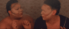Video gif. Two men with contouring makeup on their faces argue with each other.