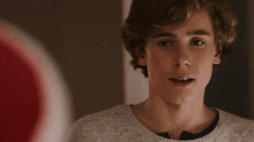 Video gif. Teen boy smirks as looks out the corner of his eye at someone and salutes with his hand quickly on his forehead.
