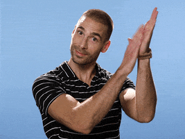 Video gif. TV personality and entrepreneur Simon Huck stares wide-eyed at us while giving us a theatrical golf clap in front of a light blue background.