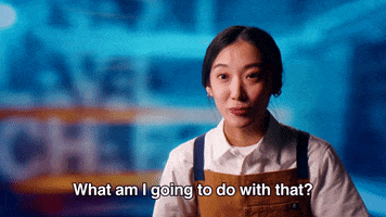 Reality TV gif. A contestant on Next Level Chef is in an interview and she smiles blankly, blinking quickly as she asks, "What am I going to do with that?"