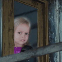 Video gif. We zoom in on a girl glancing sideways out a window with a concerned expression on her face.