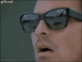 Video gif. We see a man's face in an extreme close up. He pulls a pair of sunglasses off of his eyes as he stares in open-mouthed disbelief at something.