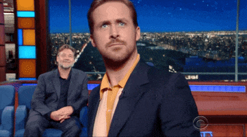 The Late Show gif. Ryan Gosling is leaving an interview and he walks towards the cameras, getting so close that he's out of focus. He frowns before raising his hand at us and waving, saying, "Bye!"