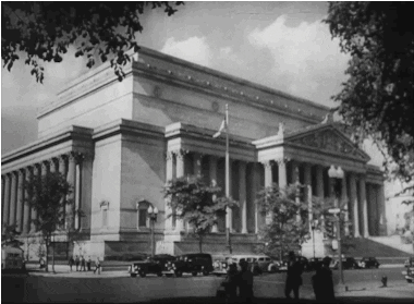 Animated gif of old, black and white footage cars passing on the street outside government building.