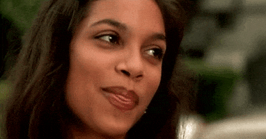 Celebrity gif. Rosario Dawson is looking upwards and a smile slowly fills her face, spreading from cheek to cheek and we see her perfect teeth appear.