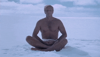Movie gif. Sitting cross-legged in the snow, we zoom in on Ron Ely as Doc Savage in Doc Savage: The Man of Bronze, calmly breathing, looking tranquil.