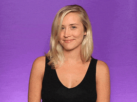 Video gif. A woman turns her head cutely and gives a small wave and a wink.