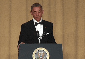 Political gif. Barack Obama stands at a podium in a tuxedo. He puts two fingers to his lips and does a literal mic drop.