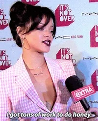 Rihanna giving interview in pink suit with caption "I got tons of work to do honey"
