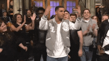 SNL gif. Drake, surrounded by SNL cast members for his goodnites, drops his arms in disbelief, then presses his hands together in display of humble gratitude.