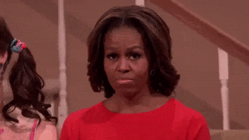 Tonight Show gif. In a skit, a bashful Michelle Obama shrugs her shoulders and raises her hand to her cheek, pouting.