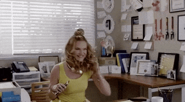 Movie gif. Nicholle Tom as Principal Statszill sits at her desk, fist pumping in celebration and ten leans back in her chair laughing.