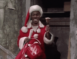 SNL gif. Eddie Murphy dressed shabbily as Santa and holding a Salvation Army bucket, rings a bell, an illegible grin frozen on his face.
