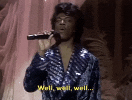 SNL gif. Eddie Murphy dressed as Prince in a curly wig and sparkly purple jumpsuit, grasps a microphone and says, "Well, well, well..." which also appears as text. He then grins and does a quick, punctuated dance move.