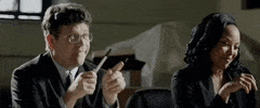 Movie gif. Sean Astin as Sam and Lynn Whitfield as Sydney in Espionage Tonight. They're interrogating someone and look pleased, as if they've caught onto something. Sam points at them with a closed lipped smile and Sydney jots something down in her notebook.