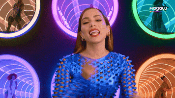 Video gif. Anitta Magalu does a sassy dance in front of several circular windows outlined in colorful light showing background dancers doing the same moves. 