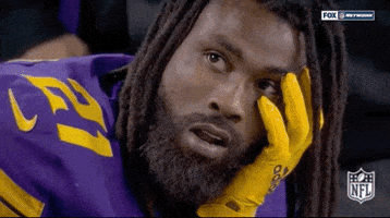 Sports gif. Bashuad Breeland of the Minnesota Vikings sits on the sidelines, resting his head on his hand. His mouth is open in shock. He looks down and covers his face with his hand, shaking head in disappointment.