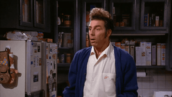 TV gif. Michael Richards as Kramer on Seinfield. He holds one hand up and quickly stops someone before stammering out, "Sorry!"
