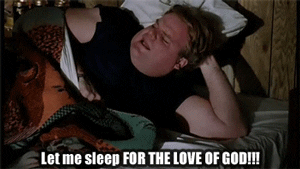 Movie gif. Actor Chris Farley as Tommy in Tommy Boy angrily leans up in bed and shouts. Text, "Let me sleep for the love of God!" 