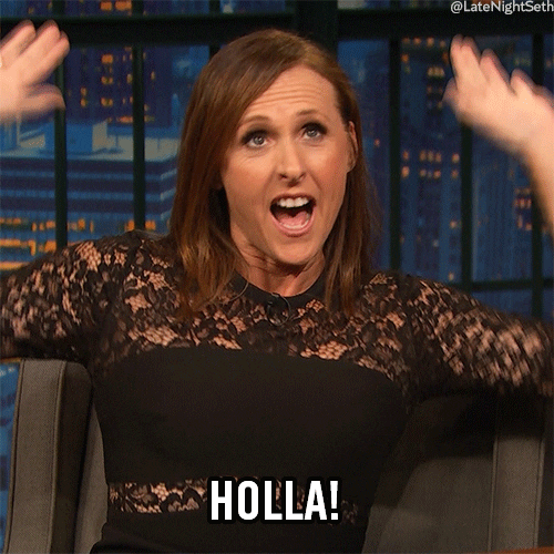 Late Night gif. Molly Shannon as the guest raises her eyebrows, throwing her hands up in the air as if raising the roof. Text, "Holla!"