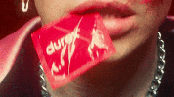 Music video gif. Yungbuld in his music video for his song, "Tissues." We're zoomed into his lips which are holding a Durex condom.