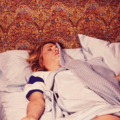 Movie gif. Kristen Wiig as Annie in Bridesmaids turns her head and moves her arms, lying in bed, looking disheveled, with a towel draped over her shoulder.