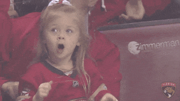 Sports gif. A young girl spectating a hockey game stretches her hands out, overcome with excitement, and screams in celebration.