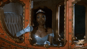 Disney gif. Brandy Norwood as Cinderella in 1997’s Cinderella sits in an ornate carriage. She leans out the door window in her sparkly blue dress. She kisses her gloved hand and blows a kiss out the window. She leans back into the carriage with a big beautiful smile on her face. 