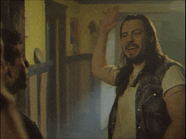 Movie gif. Andrew W.K. as Rip Stick from Dude Bro Party Massacre III gives someone a solid high five. They tightly intertwine fingers as their hands meet and don't let go as they bring their arms down.