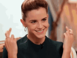 Celebrity gif. A hopeful Emma Watson holds up both hands, crossing her fingers.
