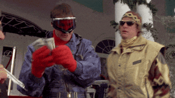 Movie gif. Wearing ski goggles, Jim Carrey as Lloyd in Dumb and Dumber hands out money to every passerby and says, “There you go. There you go.”