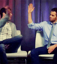 Celebrity gif. Chris Pine and Zachary Quinto high five and fist bump.