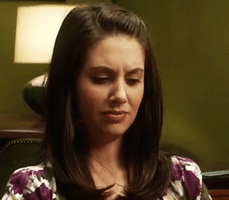 Celebrity gif. Alison Brie reacts to something with mild disbelief, expressing disagreement with a perplexed smile and furrowed eyebrows.