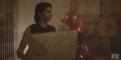 TV gif. Angel B Curiel as Esteban from Pose is shaking a large Christmas gift and listening  intently to the noise it makes.