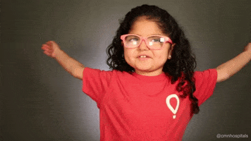 Video gif. A little girl in glasses wraps her arms around herself and gives herself a big hug. 