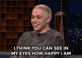 Tonight Show gif. Pete Davidson is being interviewed and he sits in a chair and looks around while saying, "I think you can see in my eyes how happy I am," and laughs at himself.