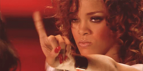 GIF da cantora Rihanna com cabelo enrolado, cara de brava fazendo não com a mão 