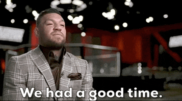 Video gif. Conor McGregor wears a brown plaid suit jacket as he sits for an interview, shrugging with a mild expression as he says, "We had a good time."